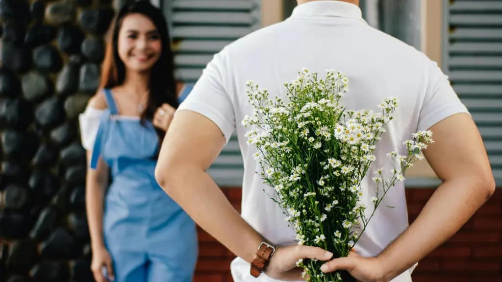 Hombre sorprende a su pareja con un ramo de flores.